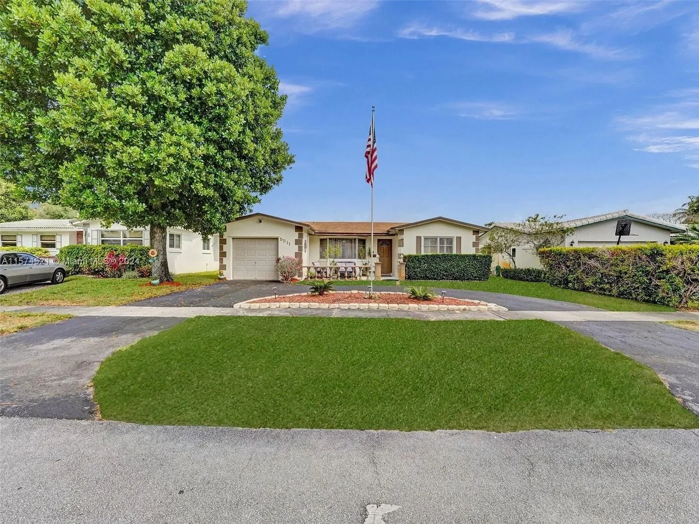 A large driveway with grass and trees in front of it.