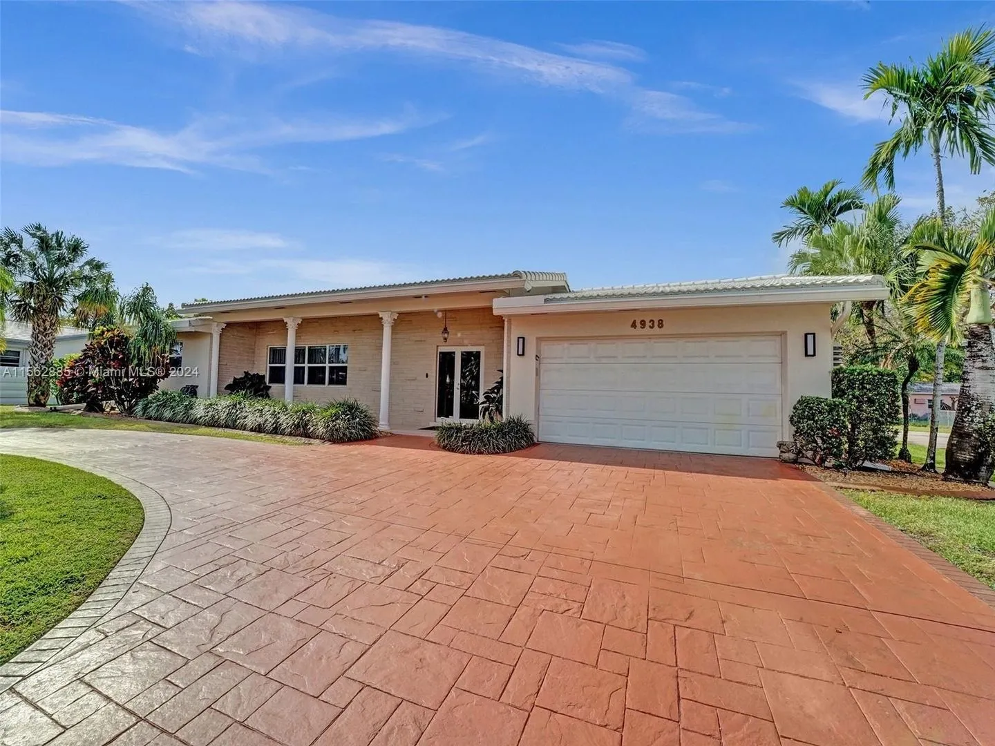 A large driveway with a garage door and palm trees.