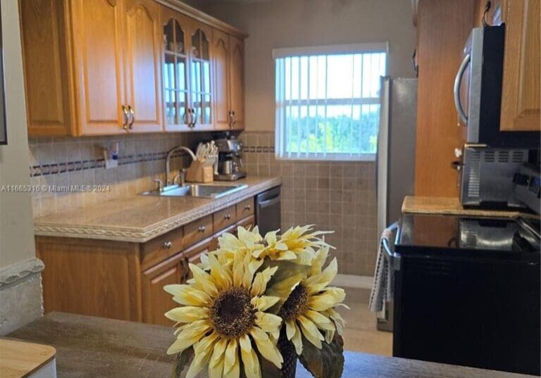 A kitchen with wooden cabinets and a vase of sunflowers.