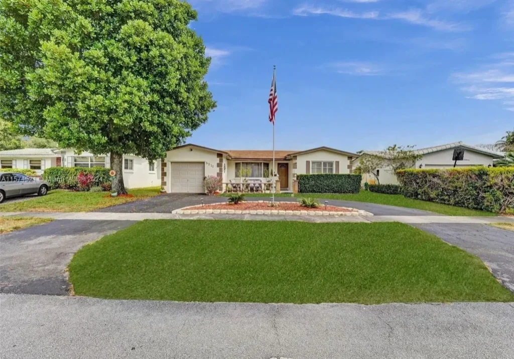 A large driveway with grass and trees in front of it.