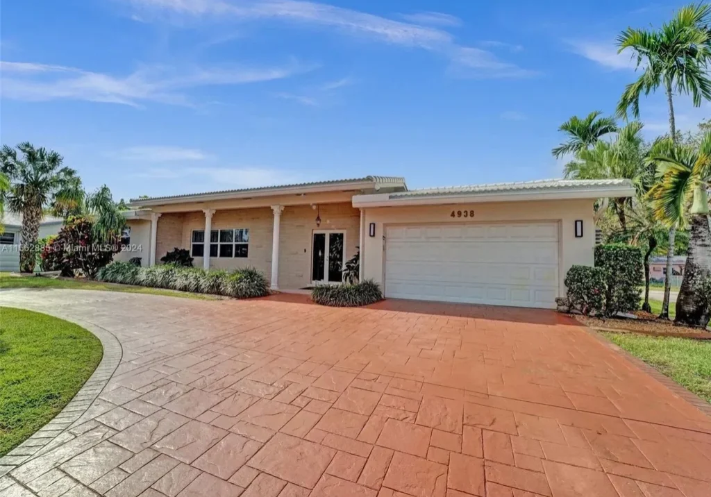 A large driveway with a garage door and palm trees.